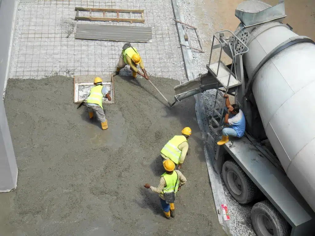 team of construction workers pouring concrete and manually leveling